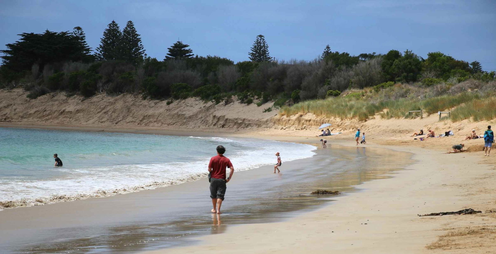 Man walking along beach in Apollo Bay, Victoria.